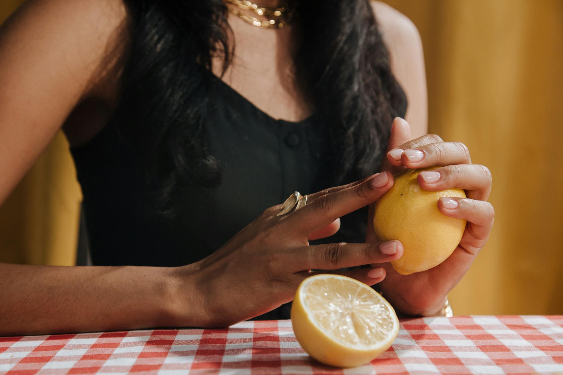 A hand holding a modern clitoral vibrator against a purple backdrop
