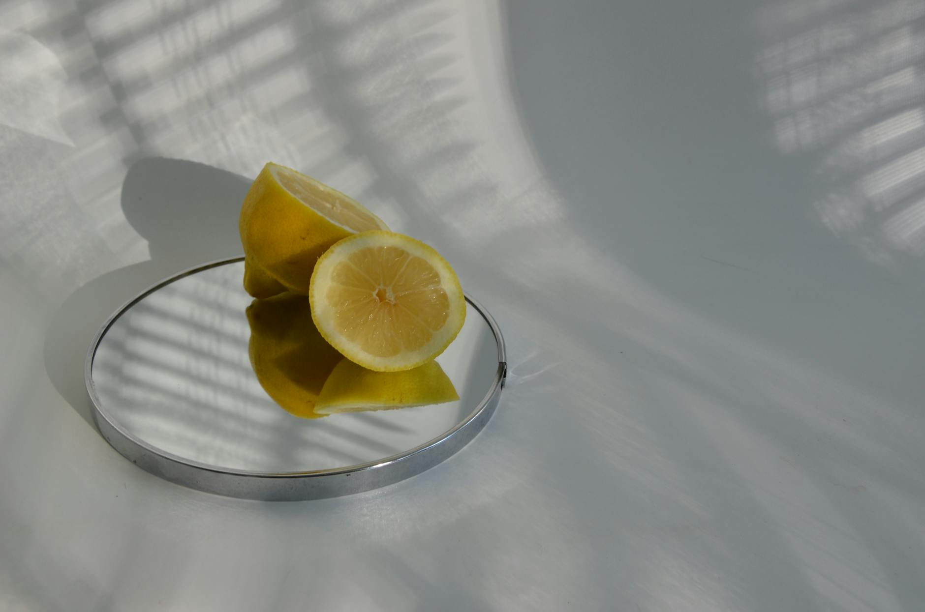 Hand holding a lemon on soft pink background, symbolizing gentle touch and fresh sensation
