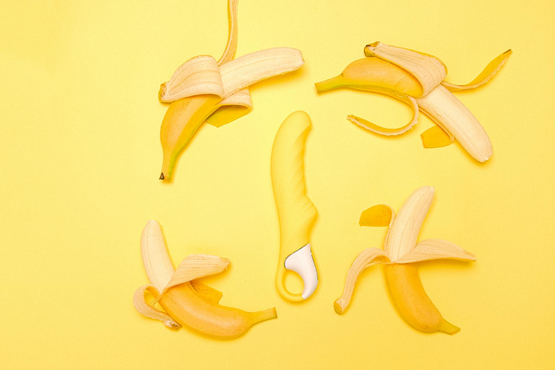 Yellow lemon clitoral vibrator on a bright yellow background surrounded by fresh lemons
