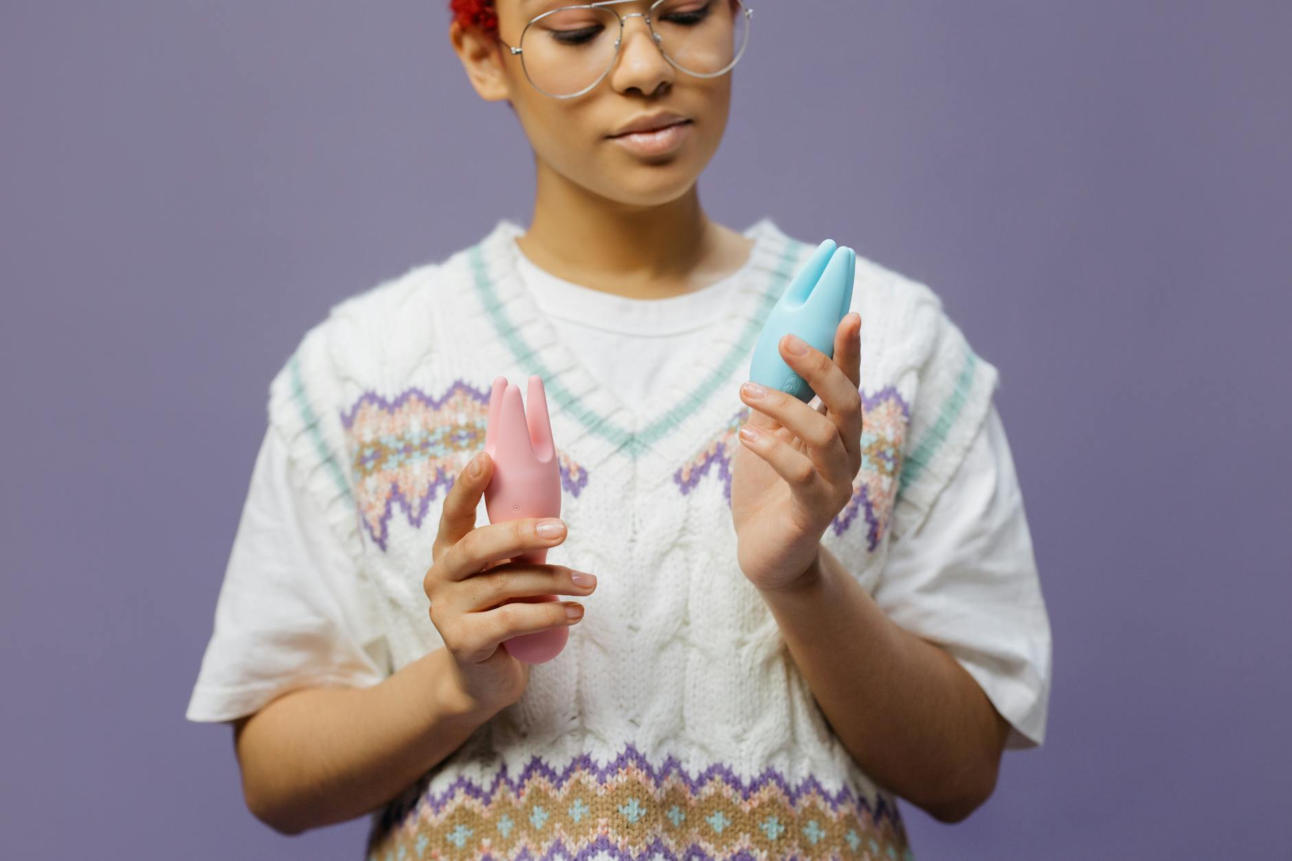A smooth teal clitoral vibrator resting on white silk fabric
