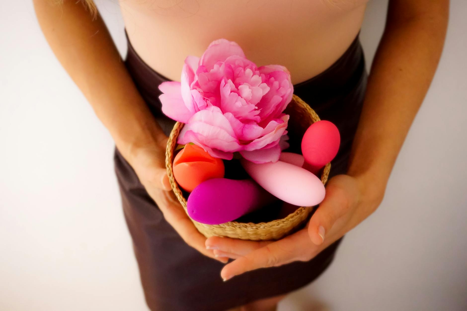 A colorful collection of vibrators and intimate wellness products arranged in a basket